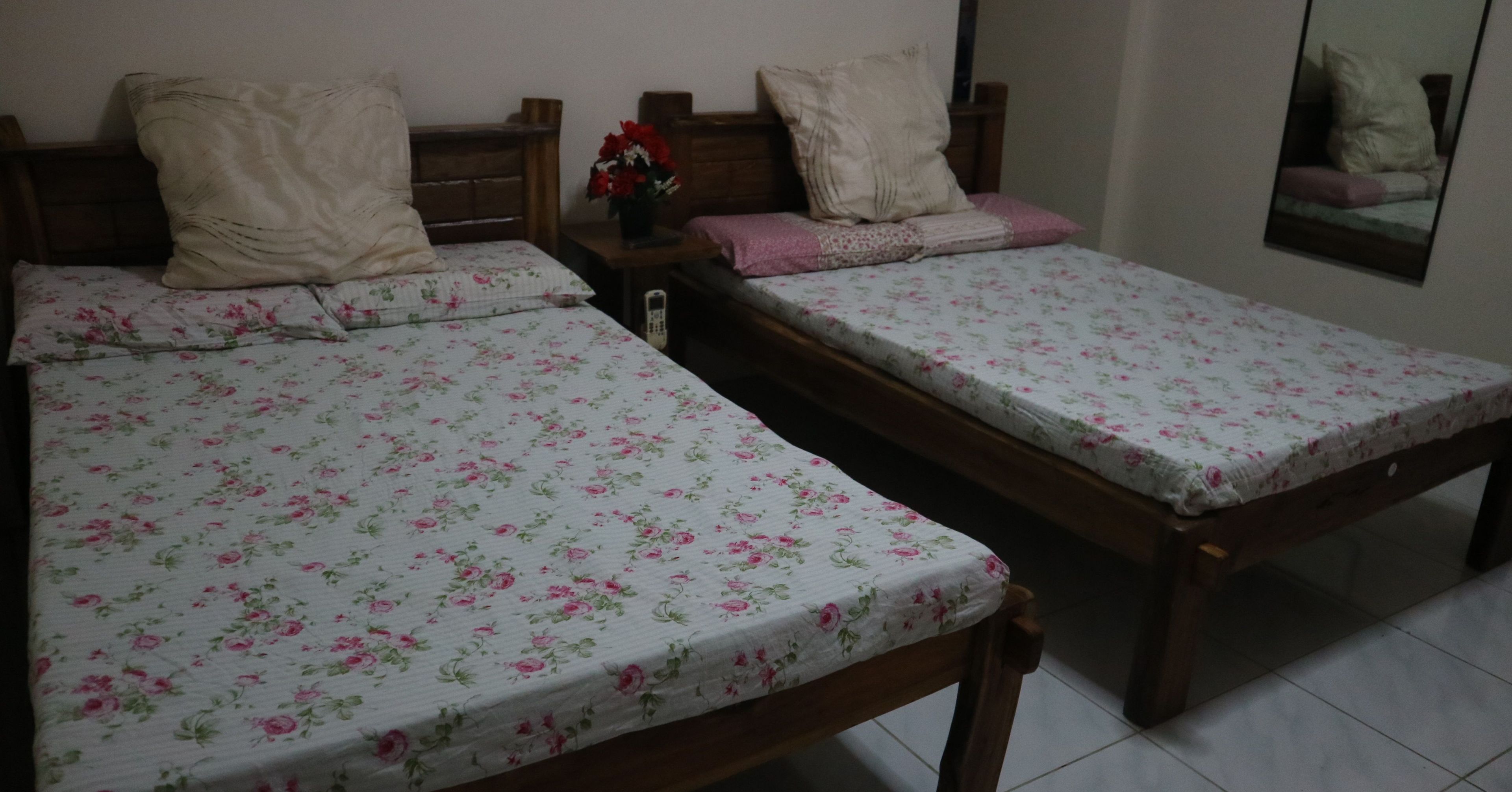 Dos camas individuales con ropa de cama estampada, cabeceros de madera y mesitas de noche con lámparas.