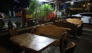 A wooden bench seating area with a table in front, surrounded by potted plants and a sign indicating a parking area. - Hundred Isles' Room Rentals and Transient House (Alaminos)
