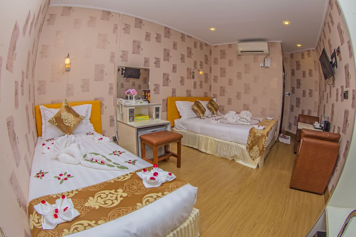 Habitación de hotel con dos camas, un escritorio, una silla y un televisor.