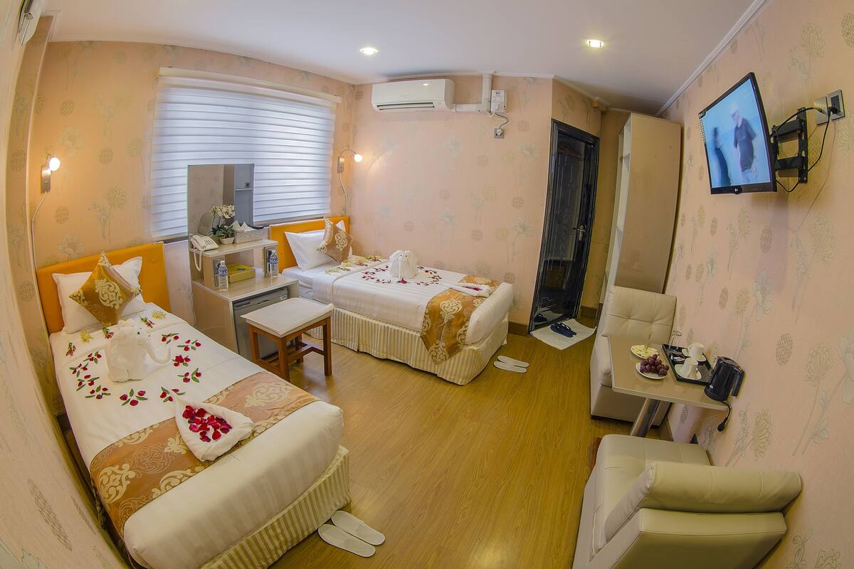 Habitación de hotel con dos camas, un escritorio, una silla, un televisor y un baño.
