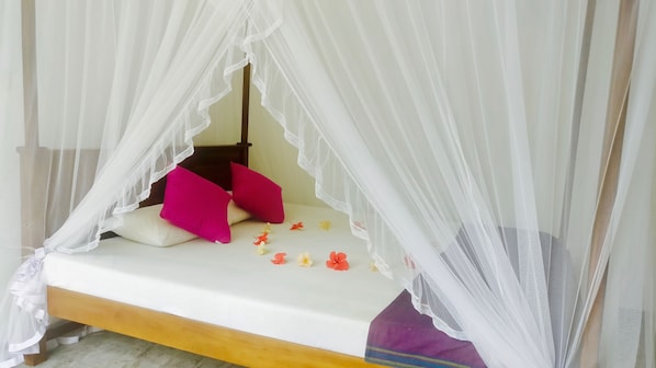 A bed with a canopy, pillows, and scattered flowers. - Aluthgedara Guest House (Unawatuna)