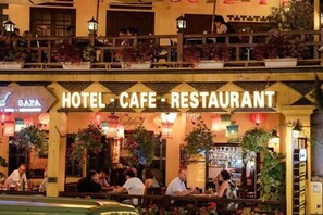 Un hotel, cafetería y restaurante con terraza y plantas decorativas.