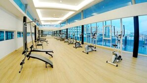 A spacious gym with various exercise equipment, large windows, and a high ceiling. - Quin Homestay (Kota Kinabalu)