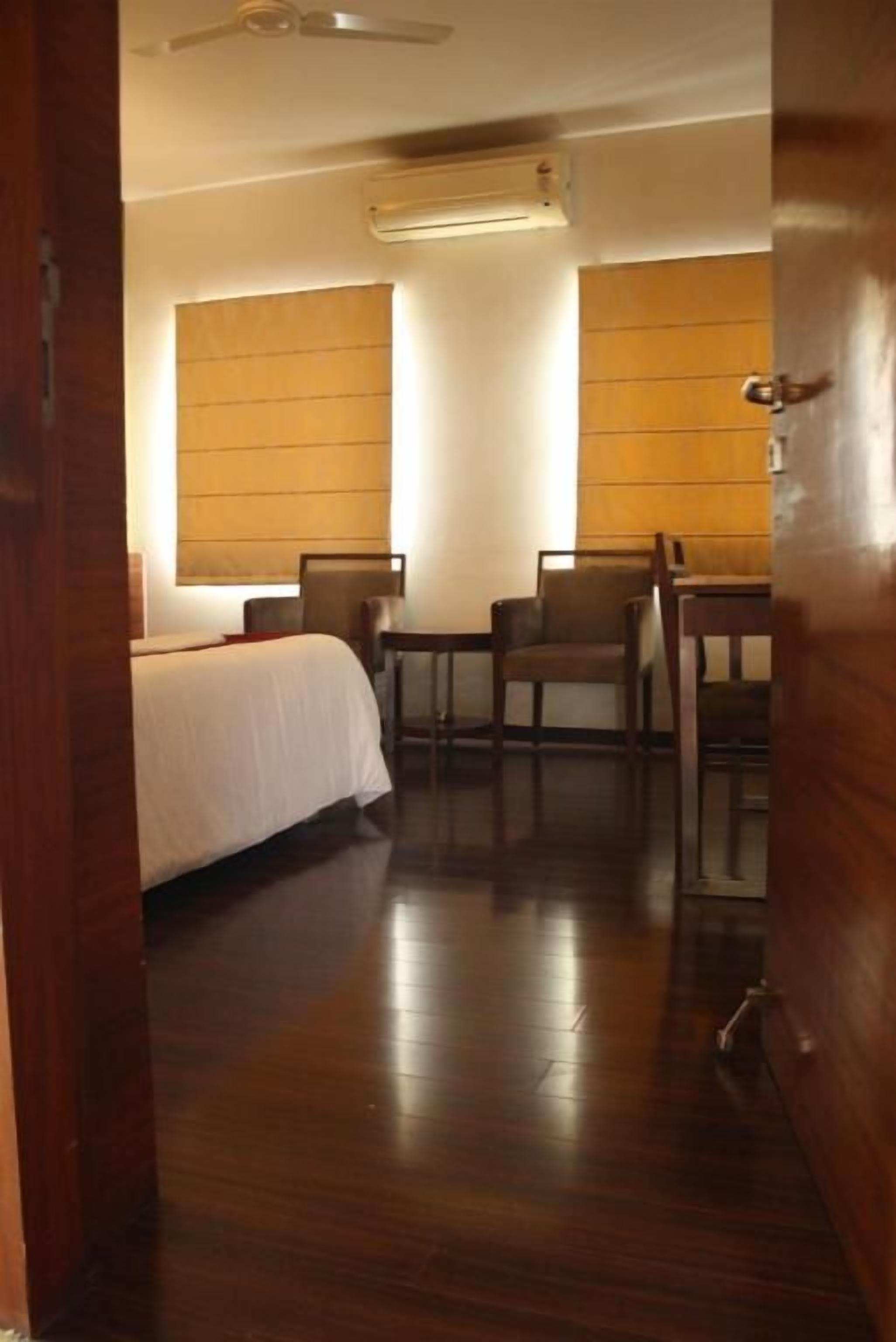 Een hotelkamer met een bed, twee stoelen, een tafel en een houten vloer.