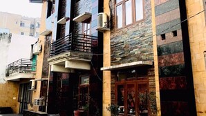 Un immeuble à plusieurs étages dont la façade est un mélange de briques et de pierres, agrémenté de balcons et équipé de climatiseurs.
