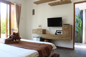 Habitación de hotel con cama, televisión de pantalla plana, escritorio de madera con cajones, refrigerador pequeño y ventana con cortinas.