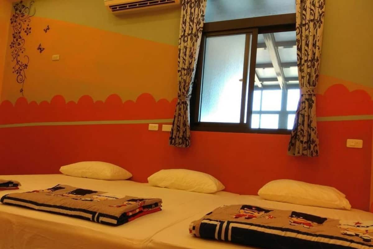 Una habitación de hotel con una cama, almohadas, un ventanal con cortinas estampadas y una pared con un diseño decorativo.