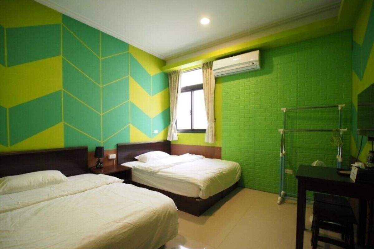 Habitación de hotel con dos camas, un escritorio y una ventana con cortinas.