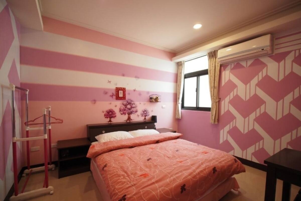 Un dormitorio con cama, cómoda, armario y ventana con cortinas.