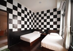 A hotel room with two single beds, a nightstand, a lamp, and a checkered wall pattern. - Passion B&B (Magong)