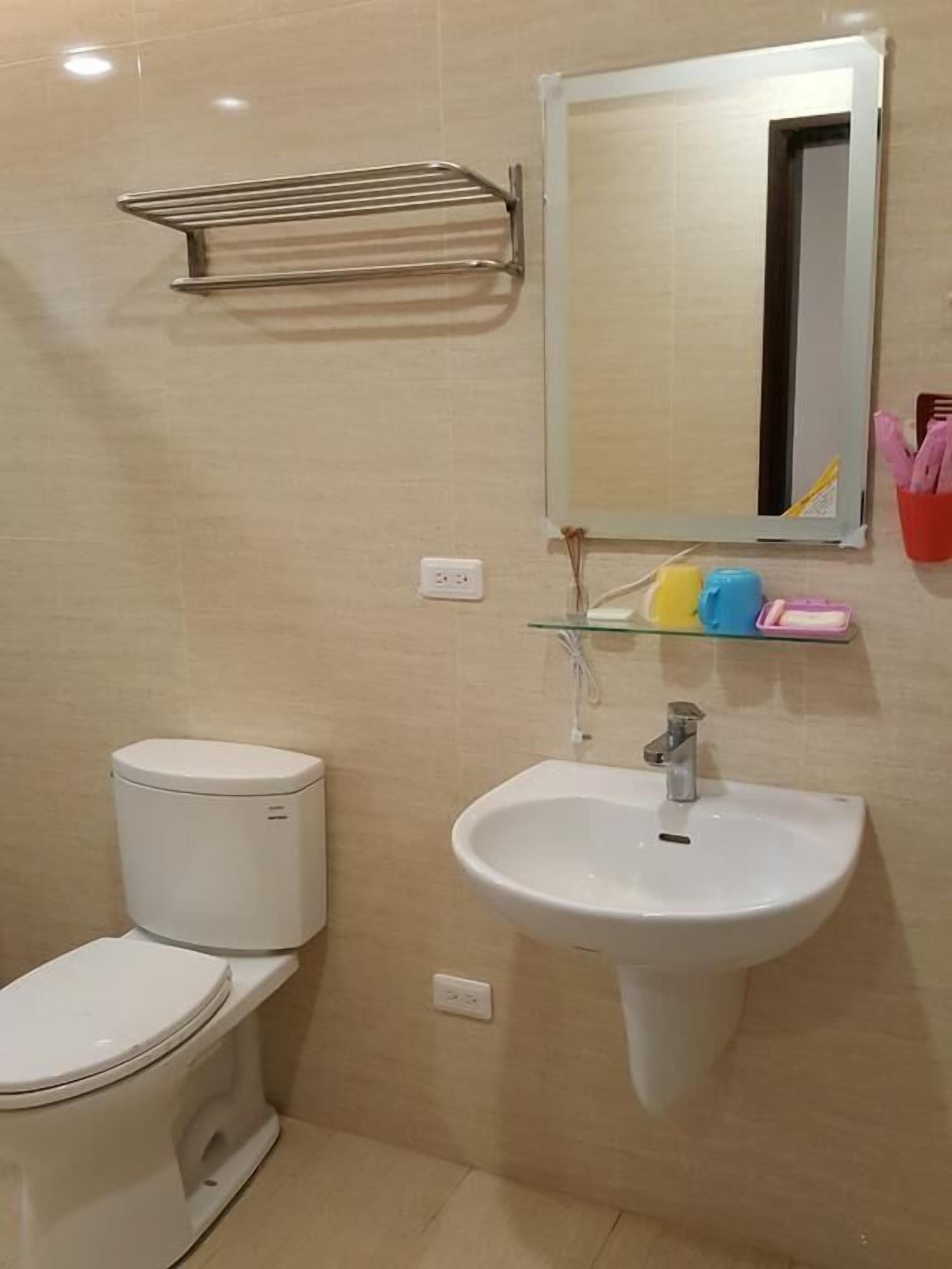 Un bagno con il water, un lavandino, uno specchio e un porta asciugamani.