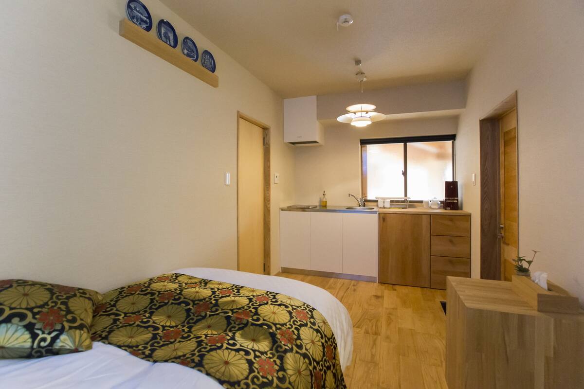A bedroom with a bed, a small kitchenette, and a bathroom.