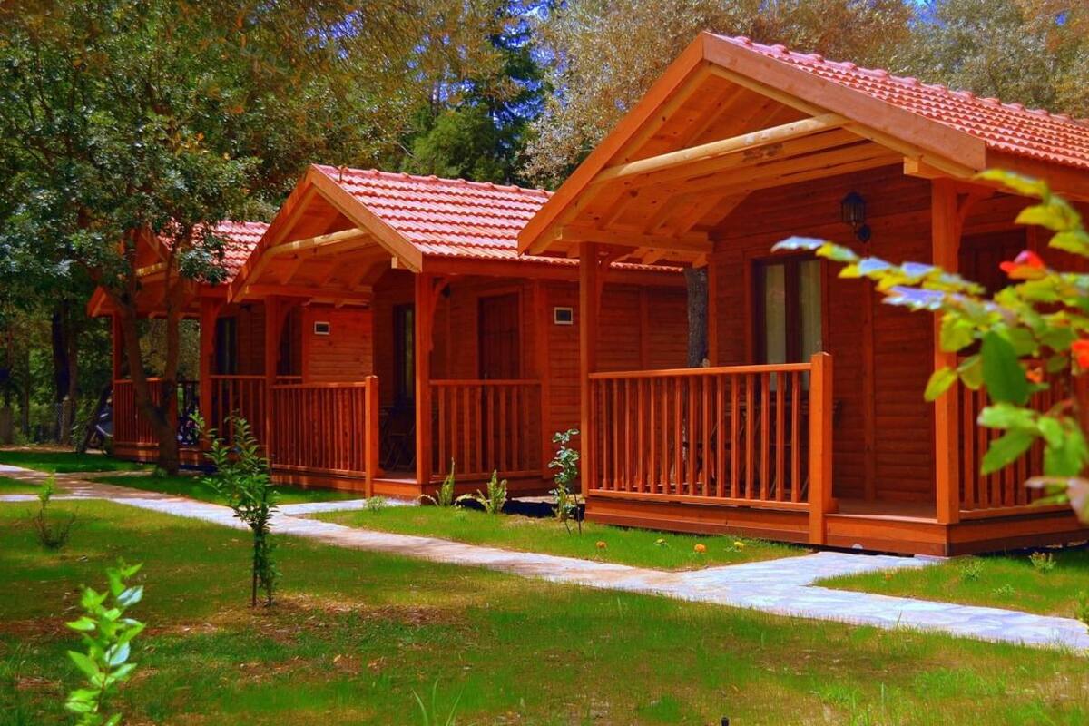 A row of wooden cabins with red roofs, each featuring a balcony and a door.