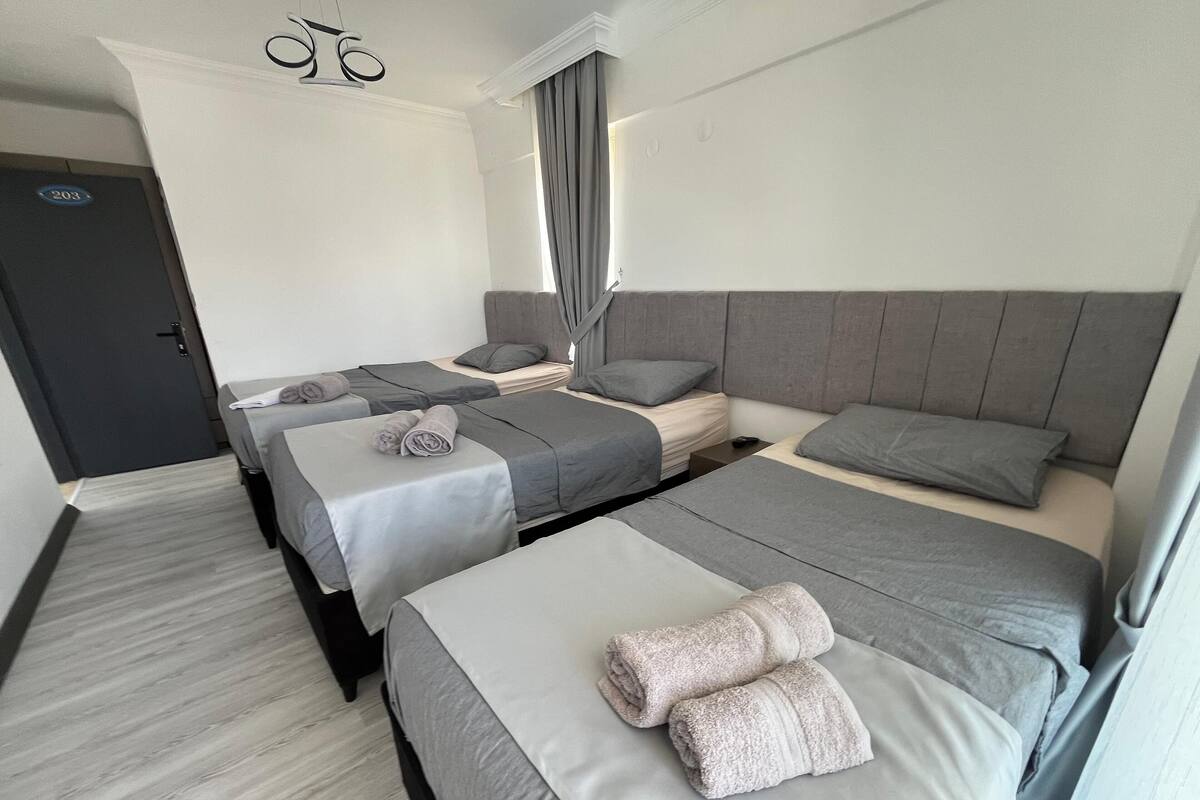 A hotel room with two single beds, a double bed, and a door marked with the number 203.
