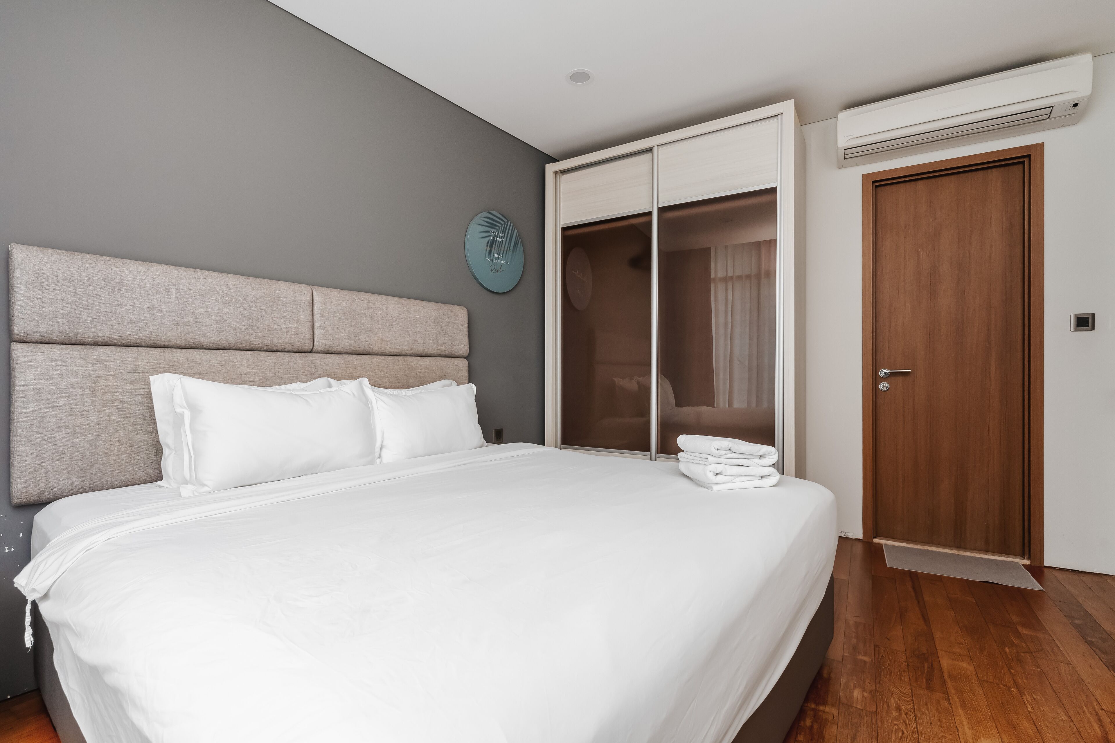 A modern hotel room with a large bed, a wooden wardrobe, and a built-in closet.