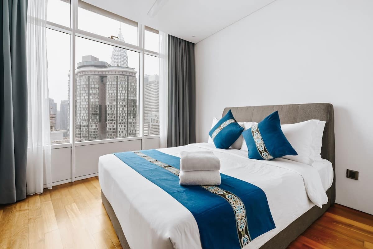 A hotel room with a large bed, a view of a cityscape through the window, and a modern design.