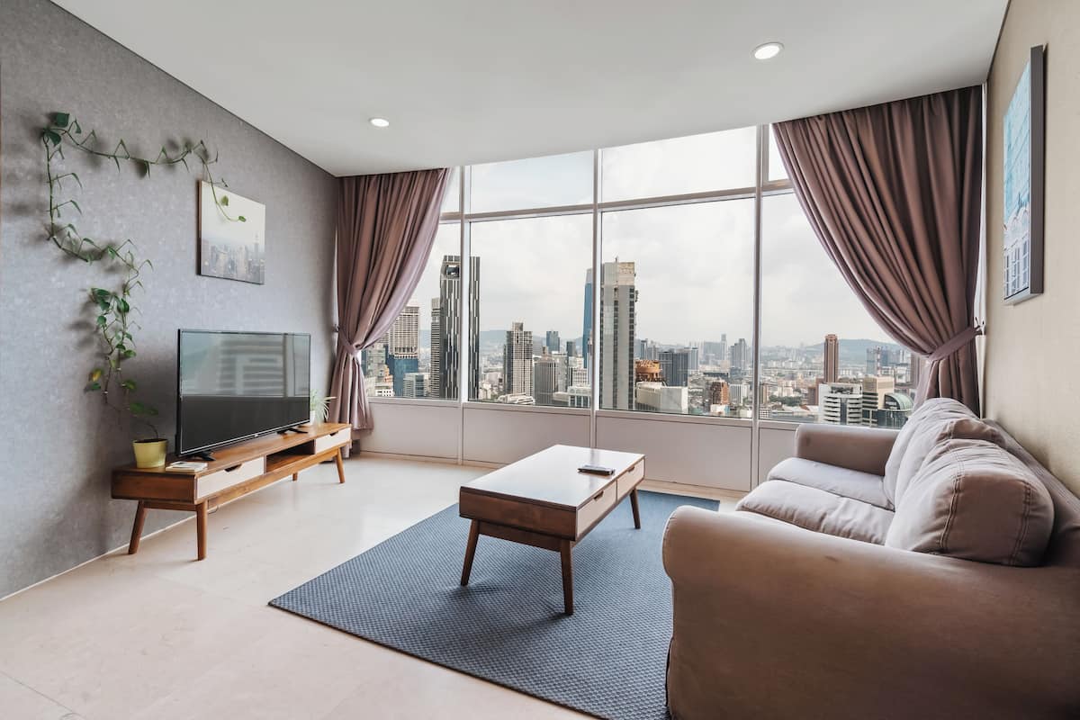 A modern living room with a large window, a flat-screen TV, a sofa, and a coffee table.