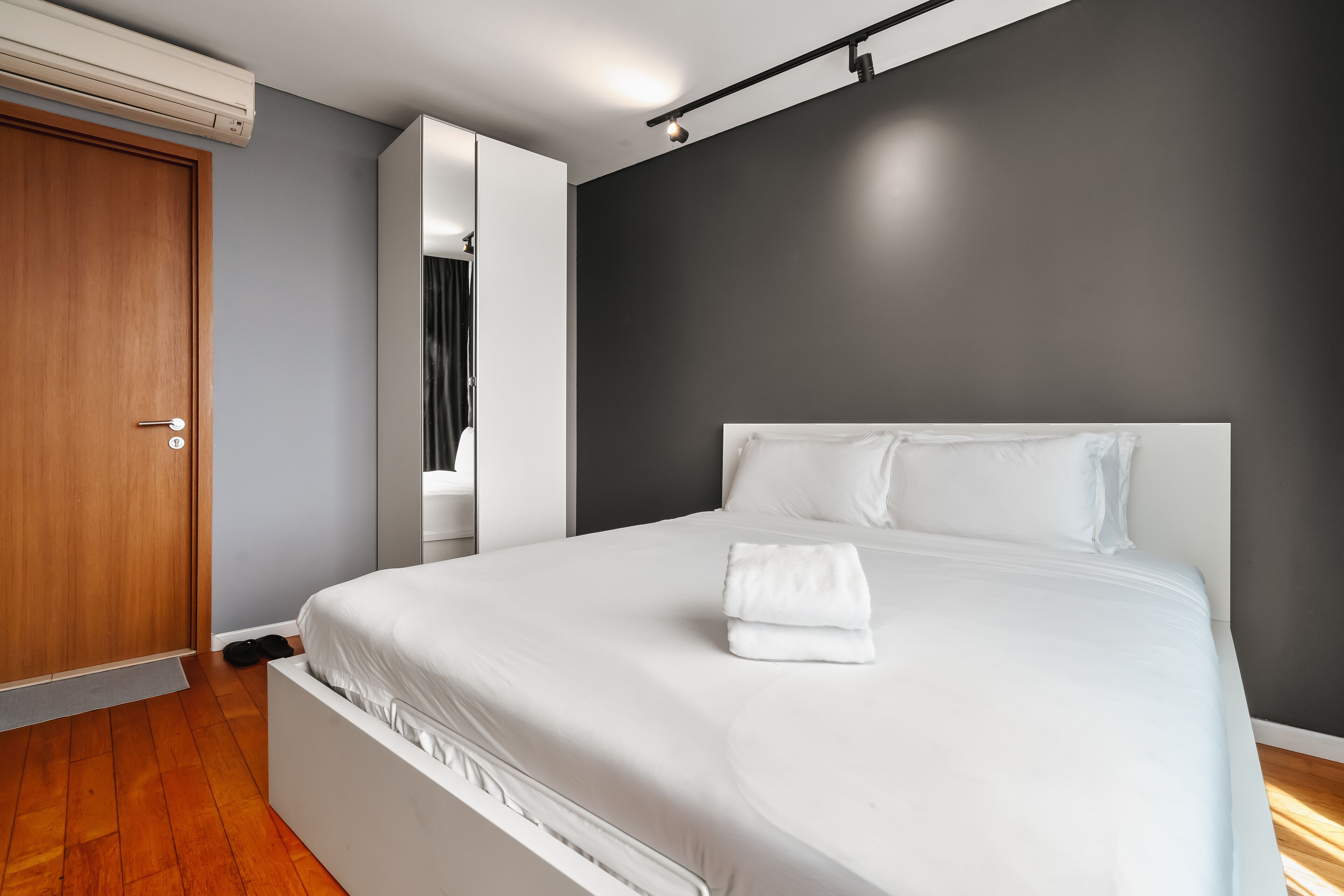 Una camera da letto moderna con un letto grande, una porta in legno e un armadio a muro.