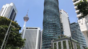 Un moderno grattacielo con facciata curva, una torre imponente e un hotel caratterizzato da un motivo a griglia delle finestre.