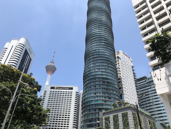 Un rascacielos moderno con fachada curva, una torre destacada y un hotel con un diseño de ventanas enrejadas.