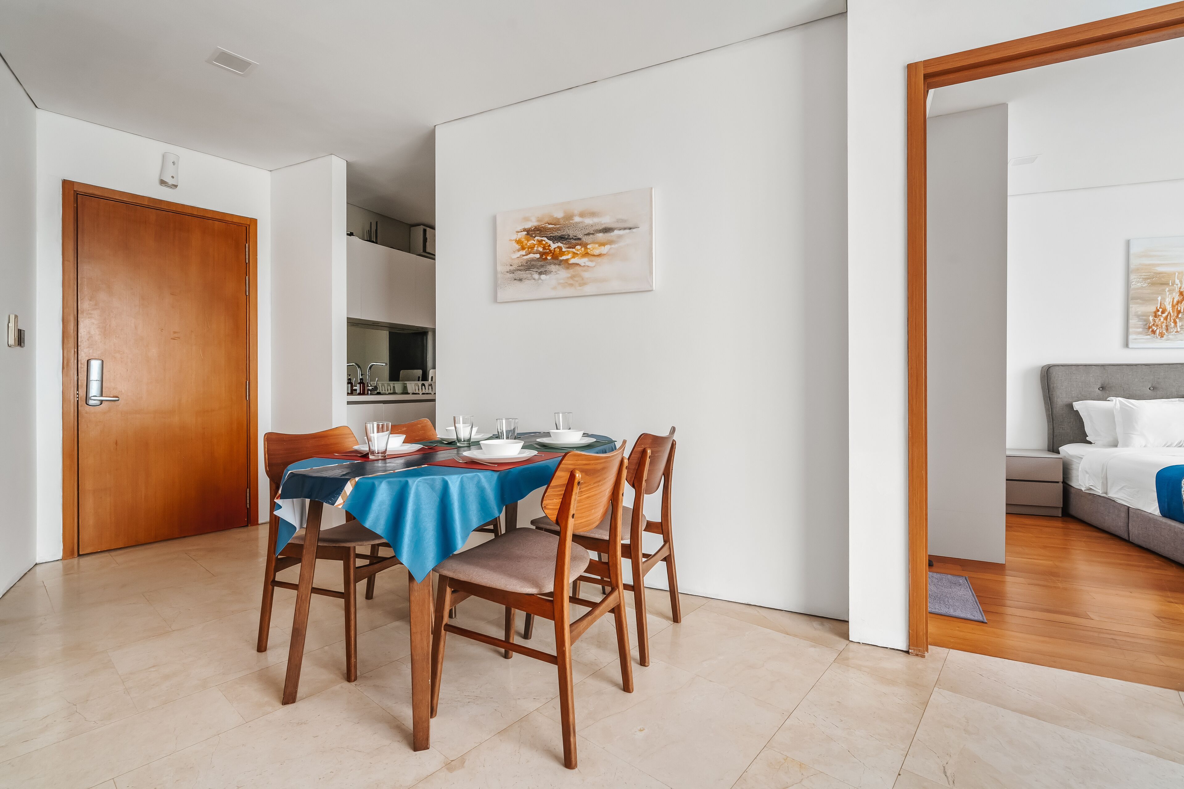 Comedor con una mesa dispuesta para cuatro personas, sillas de madera y mantel azul.