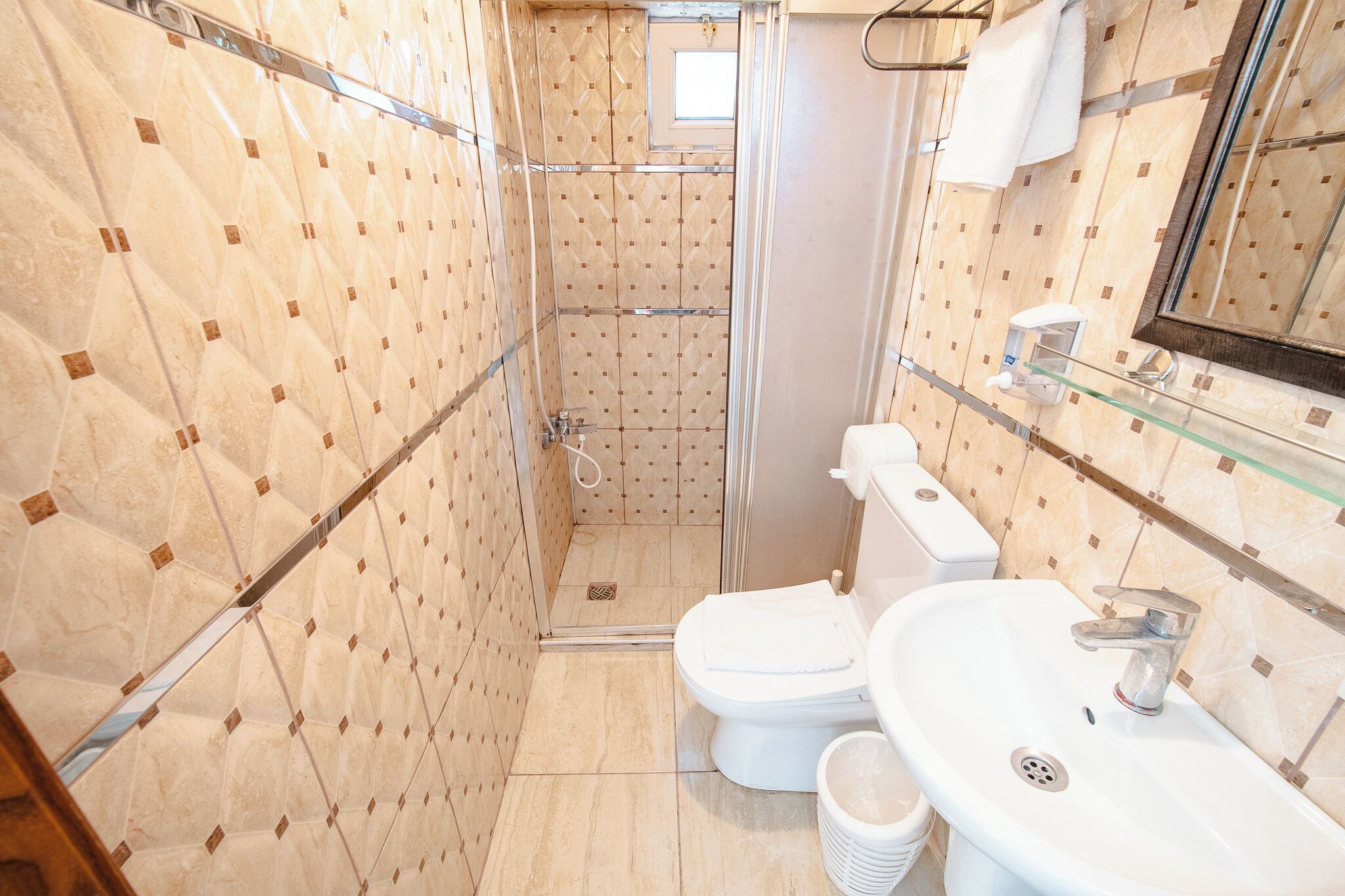 A bathroom with a shower, toilet, and sink, tiled walls, and a mirror.