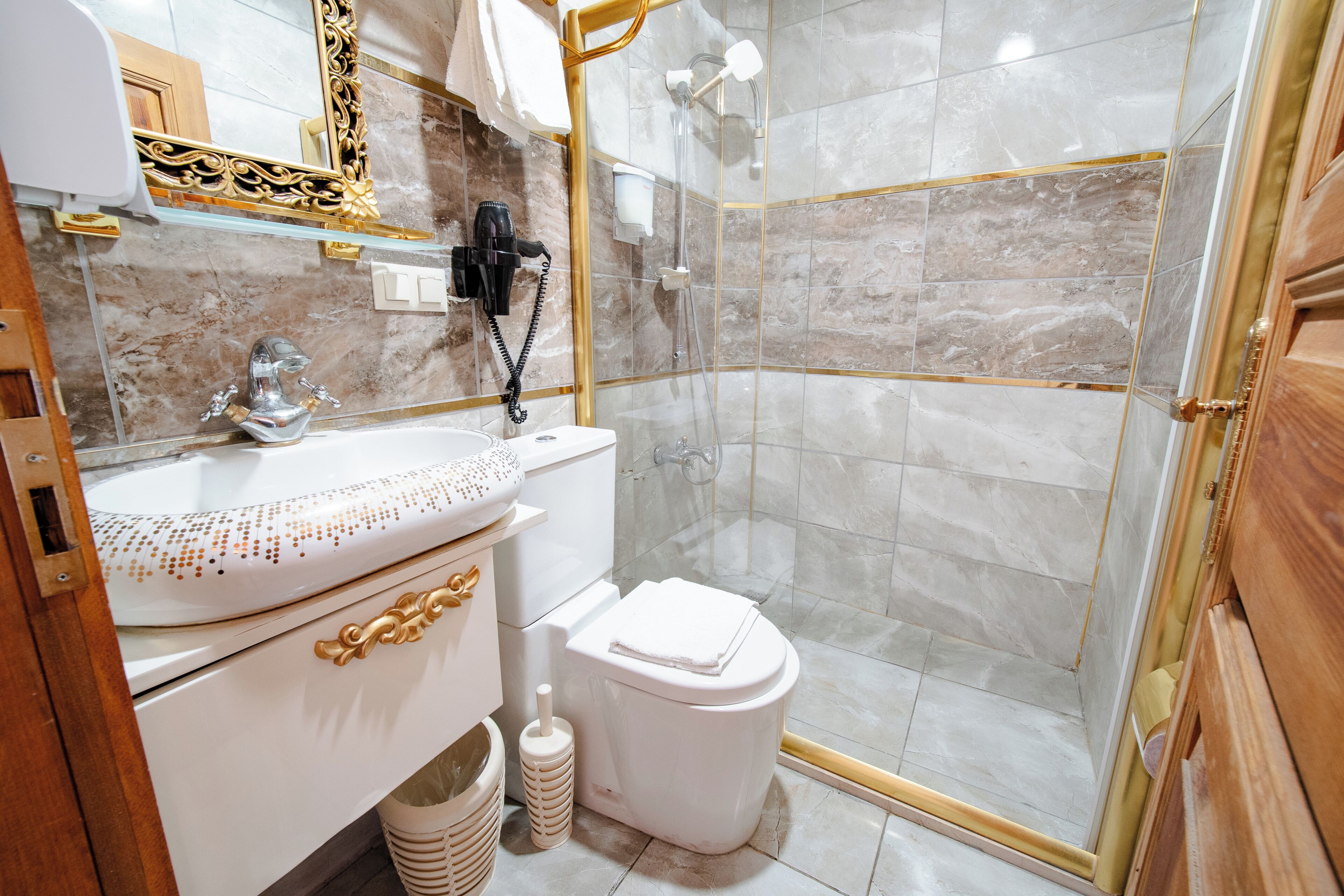 A bathroom with a glass shower enclosure, a white toilet, and a vanity with a decorative sink.
