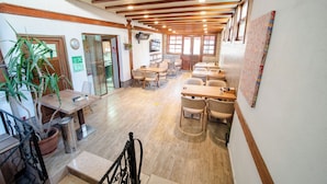 Un ristorante con travi in legno, diversi tavoli, sedie e una pianta in vaso.