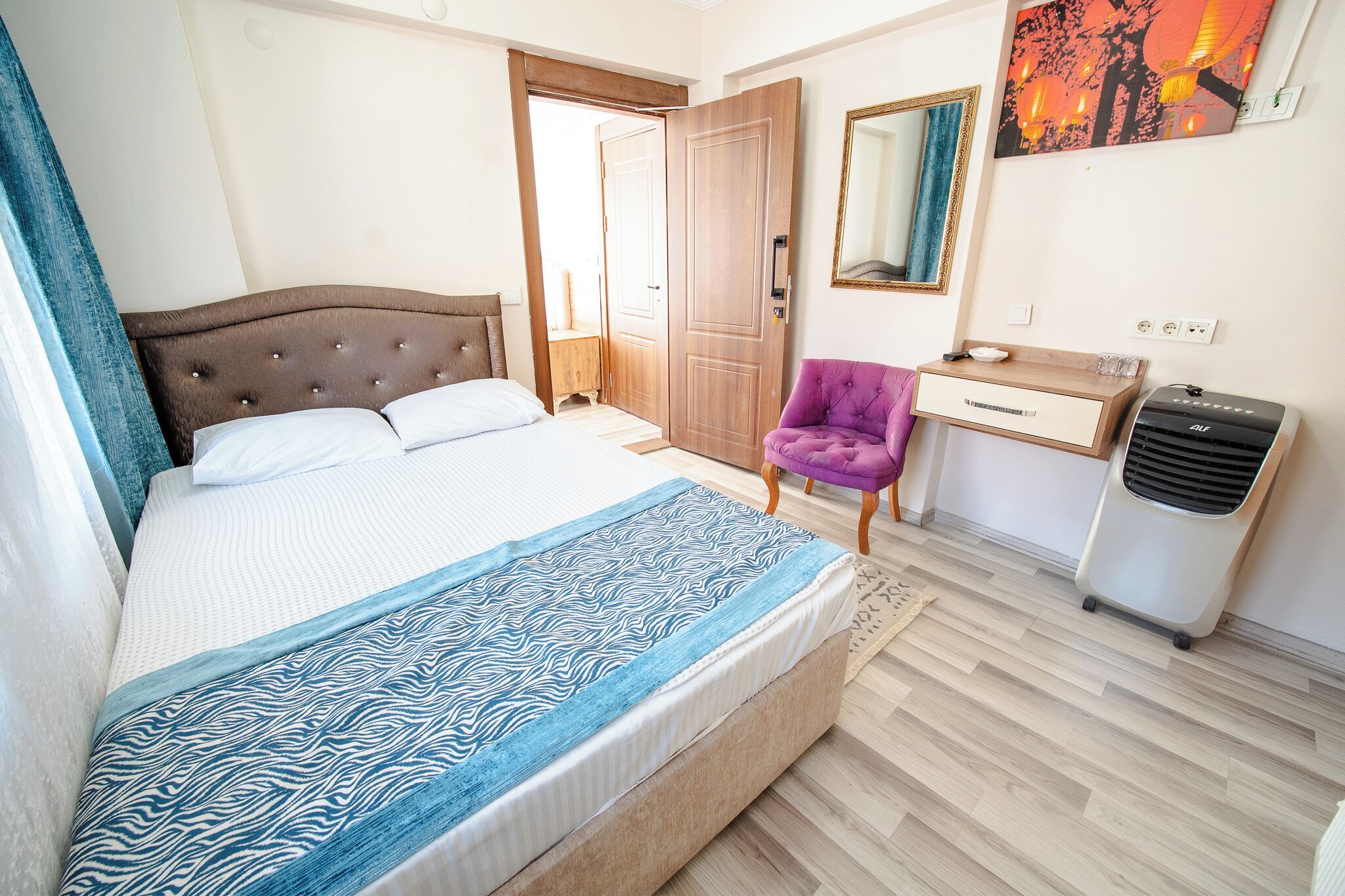 Ein Schlafzimmer mit einem Bett, einem Schreibtisch, einem Stuhl, einem Heizkörper und einer Tür zu einem anderen Raum.