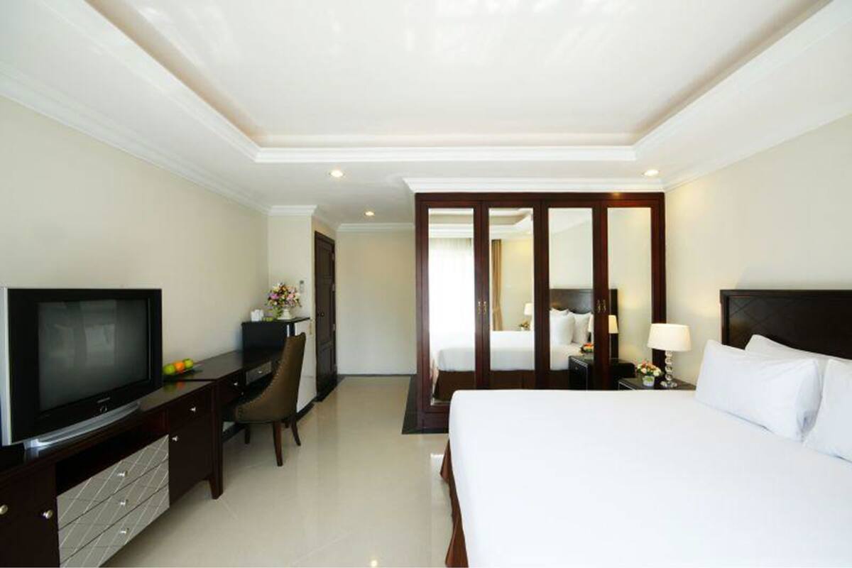 A hotel room with a bed, a TV, a desk, and a wardrobe.