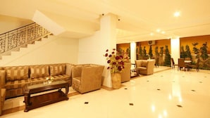 A spacious lobby with a staircase, a sofa set, a coffee table, and a decorative vase.