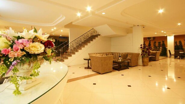 A spacious lobby with a marble floor, a staircase, and a seating area with sofas and a coffee table.
