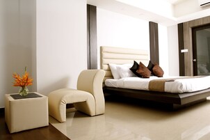 A modern bedroom with a large bed, a small bedside table, and a chair.