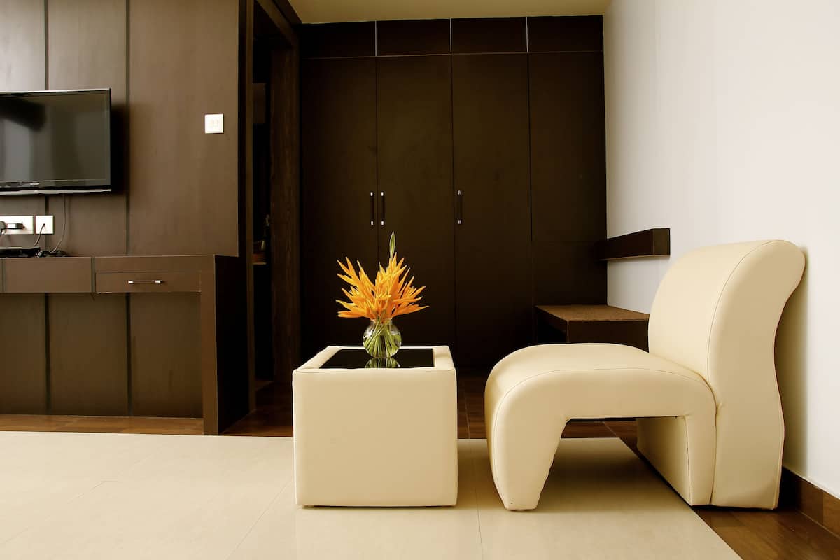 Una sala de estar moderna con un televisor de pantalla plana, una mesita auxiliar blanca con un florero, un sofá color crema y armarios de madera oscura.
