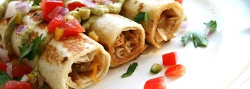 A plate of burritos with guacamole and diced tomatoes.
