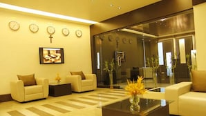 A modern lobby with sofas, a coffee table, and a large mirror. - Imperial Regency (Kanayannur)