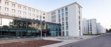 Un bâtiment moderne doté d’une façade en verre et d’un espace paysager agrémenté de paillis et de plantes en pot.