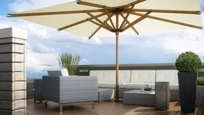 Une terrasse sur le toit, dotée d’un grand parasol, de meubles en osier et de plantes en pot.
