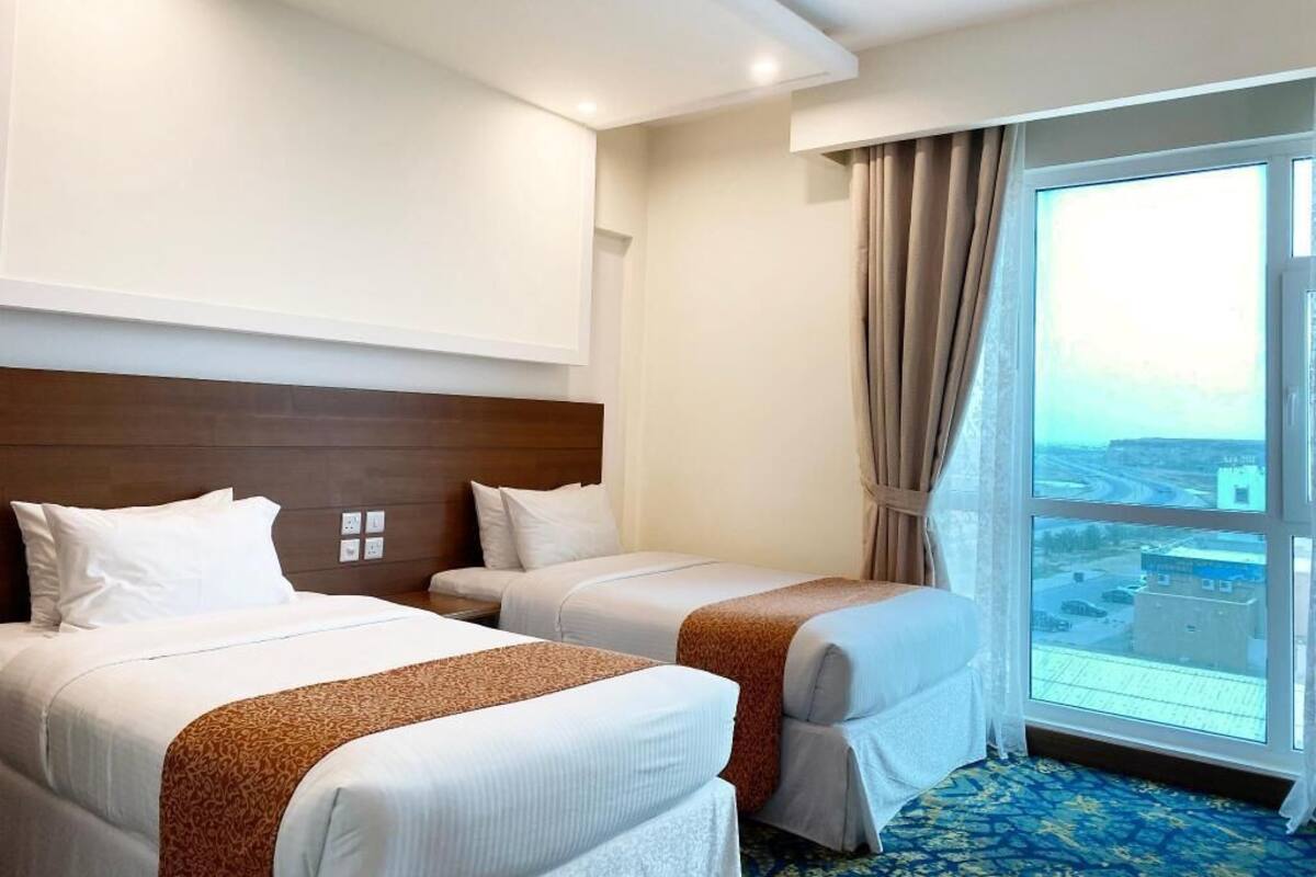 A hotel room with two beds, a large window with a city view, and a modern design.