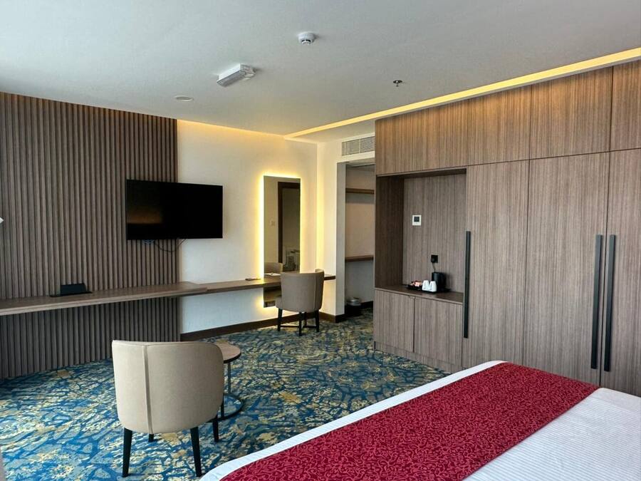 Une chambre d’hôtel comprenant un lit, un bureau, une chaise, une télévision et une armoire.