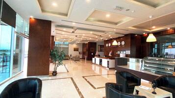 Un moderno vestíbulo de hotel con mostrador de recepción, zona de estar y amplios ventanales.