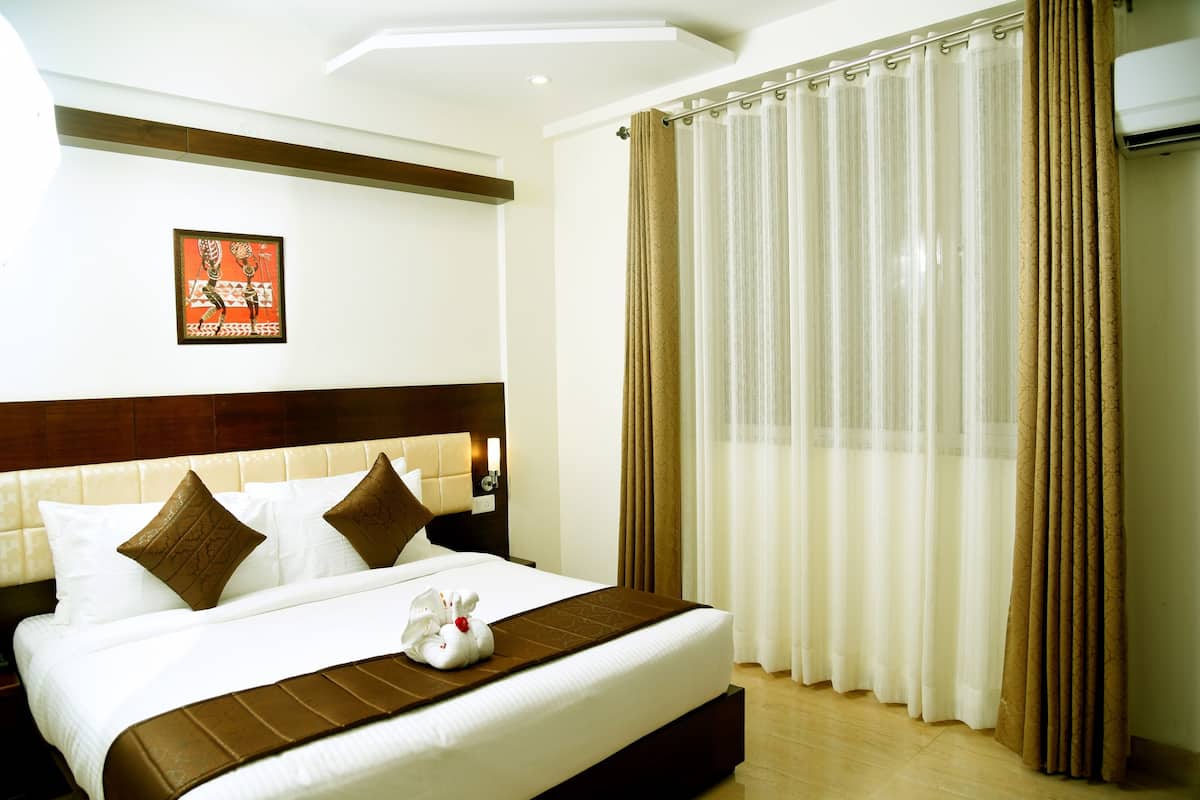 A hotel room with a large bed, a headboard, a wall-mounted artwork, and a window with curtains.