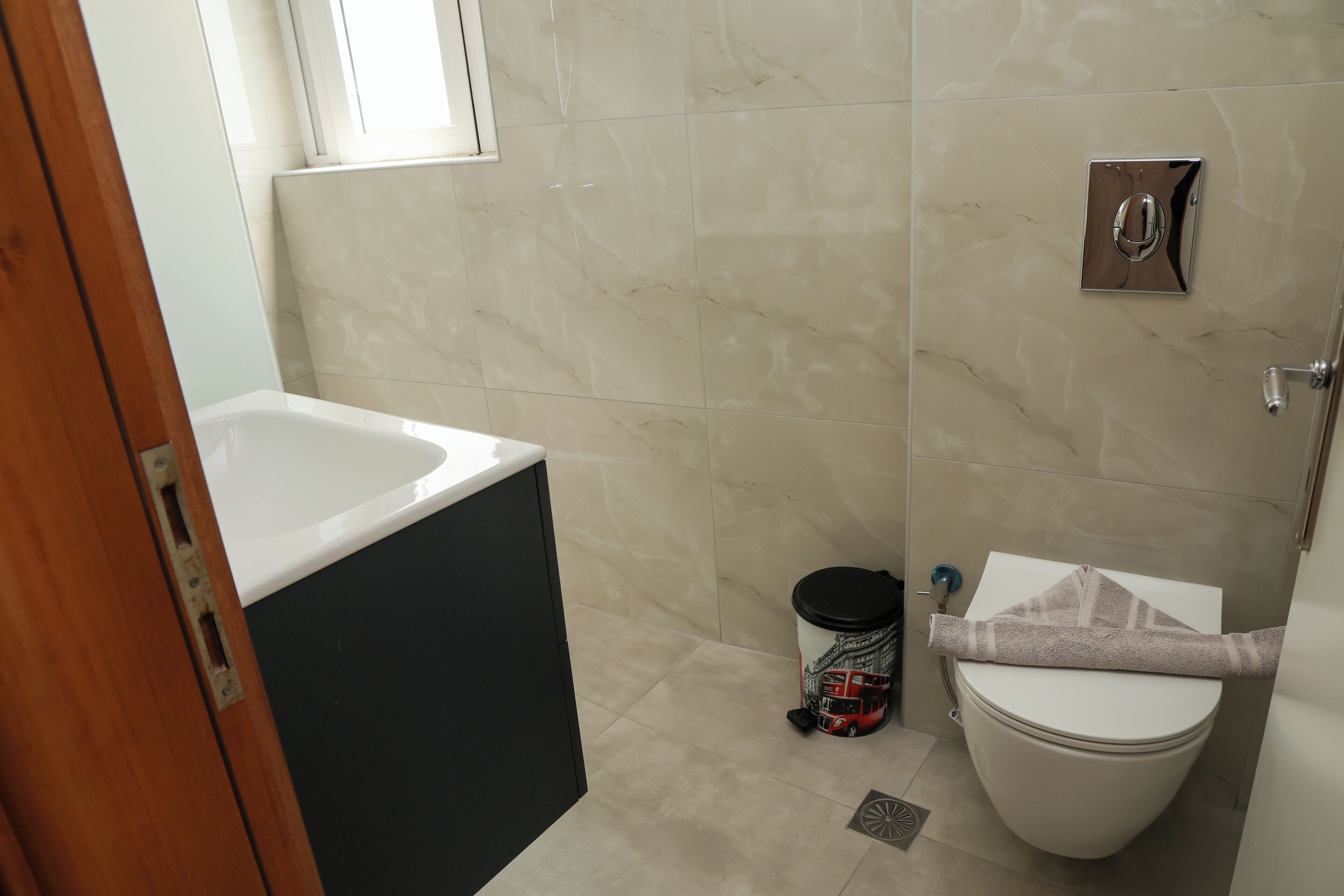 A bathroom with a bathtub, toilet, and a trash bin.
