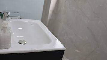 A bathroom with a white sink, a bottle of soap, and a window.