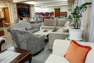 Una sala de estar moderna con sofás, sillones, una mesa de centro y un televisor.