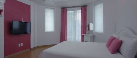 Un dormitorio con una cama grande, un televisor instalado en la pared y una lámpara en el techo.