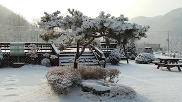 Un parque cubierto de nieve con una escalera de madera, bancos y una mesa de picnic.