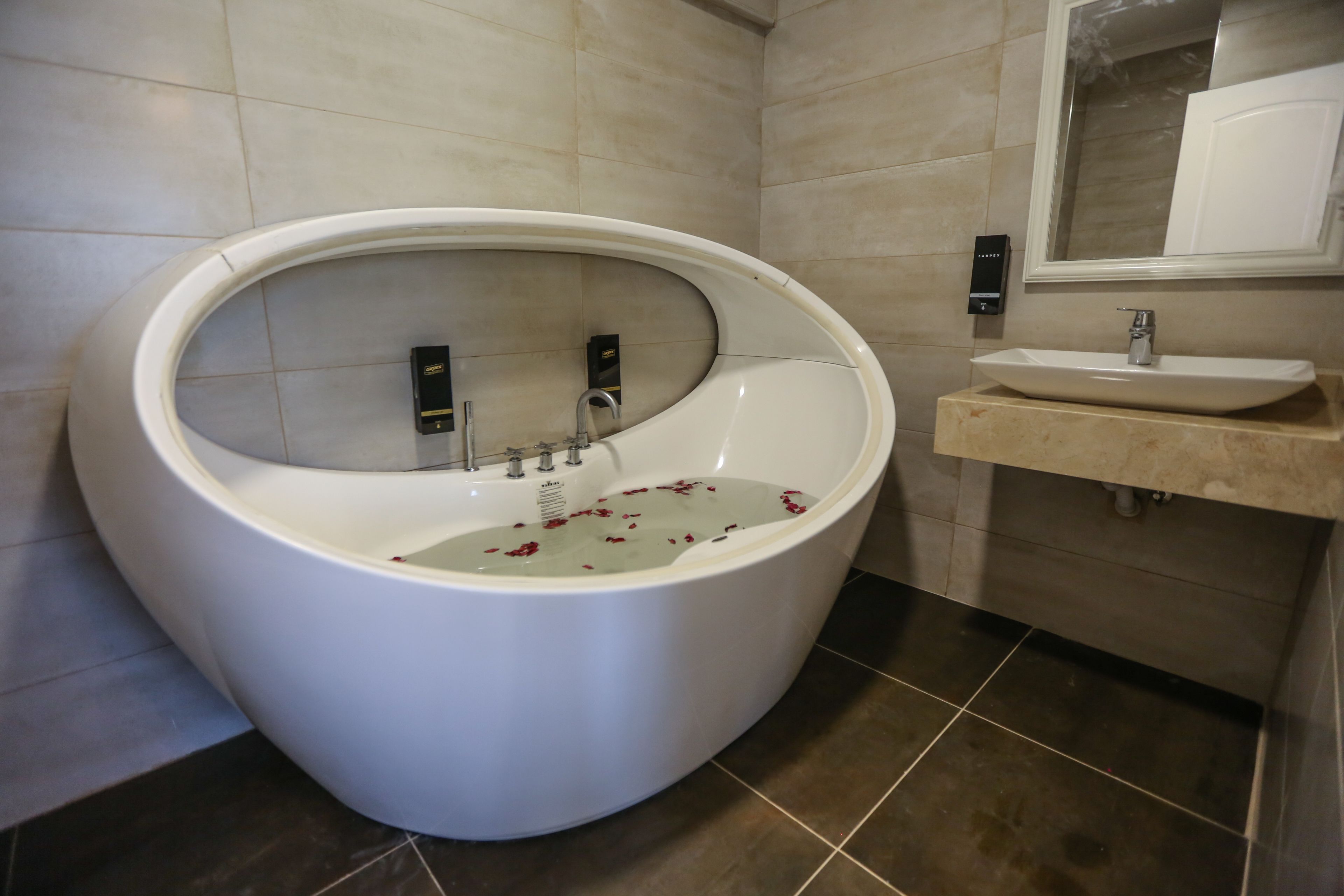 A modern bathroom with a freestanding bathtub, a sink, and a mirror.