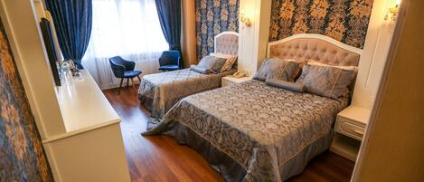 A hotel room with two beds, a desk, a chair, and a large window with curtains.