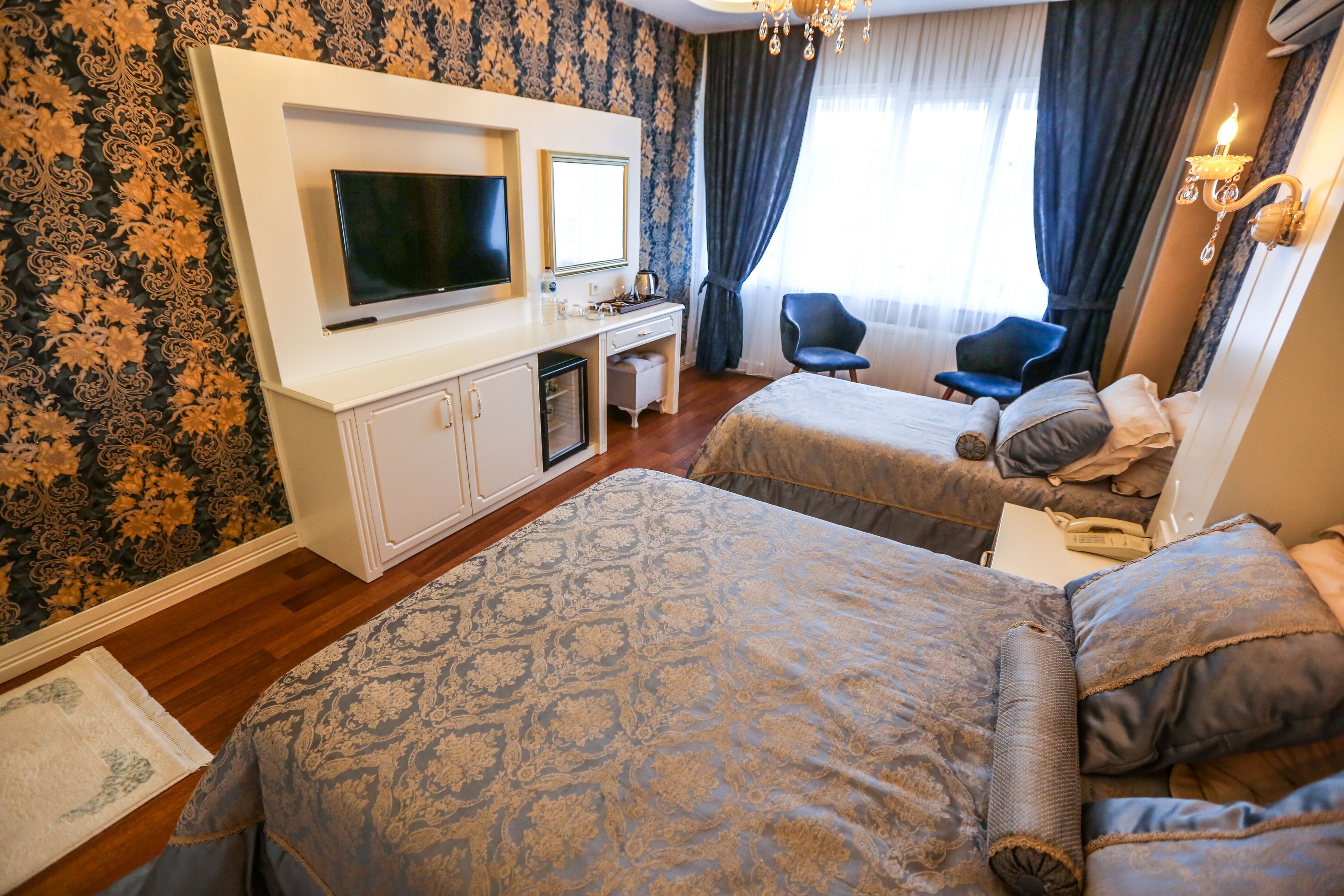 Una habitación de hotel con dos camas, televisor, escritorio y una silla.